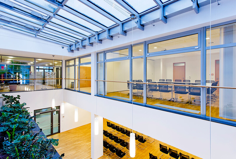 Foto einer Übersicht der angebotenen Veranstaltungsräume. Das Foto wurde von der Galerie des großen Konferenzraums im Atrium aufgenommen. Durch die großen Fenster erhält man einen Blick in die Seminarräume 1 und 2 im ersten Obergeschoss.